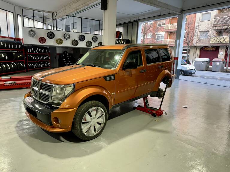 Interior taller pneumáticos Toni con un coche SUV naranja que se esta reparando